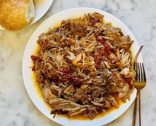 Smoky Pulled Pork and Peppers on white plate next to a plate of buns.