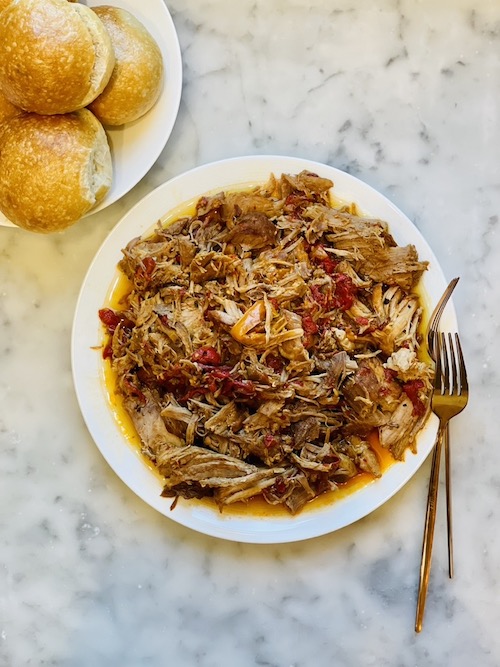Smoky Pulled Pork and Peppers on white plate next to a plate of buns.