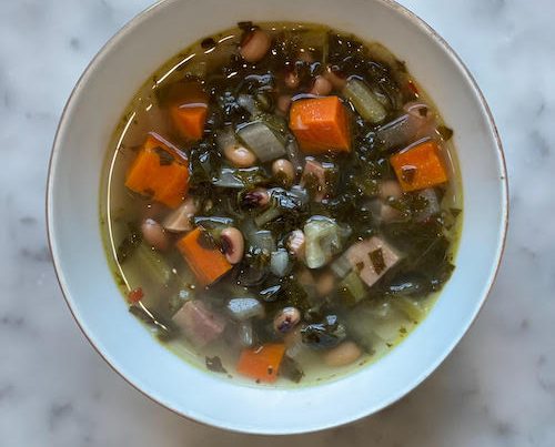 Black eyed pea soup with ham in a white bowl.