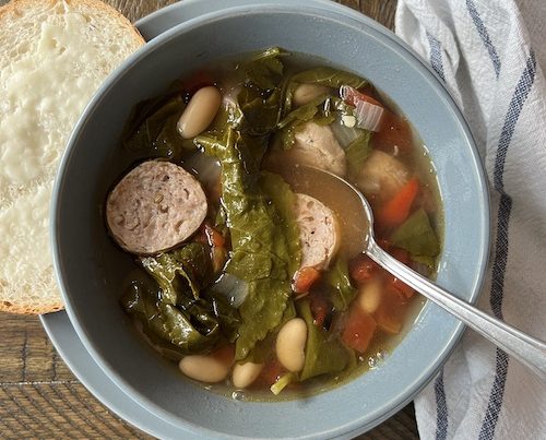 A blue bowl filled with sausage and white bean stew.