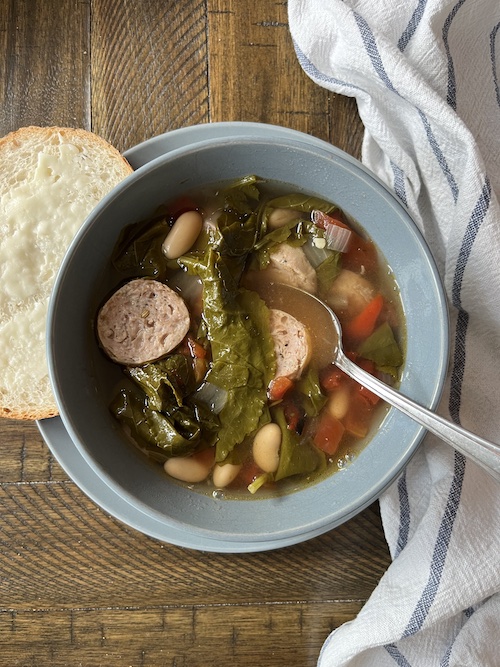 A blue bowl filled with sausage and white bean stew.