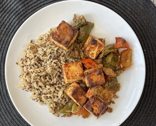 Tandoori paneer with brown rice on a white dinner plate.