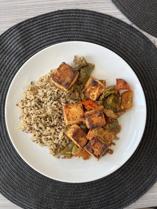 Tandoori paneer with brown rice on a white dinner plate.