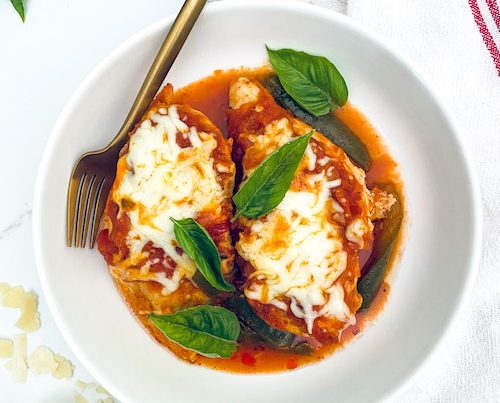 Marinara chicken breast topped with mozzarella in a white bowl.