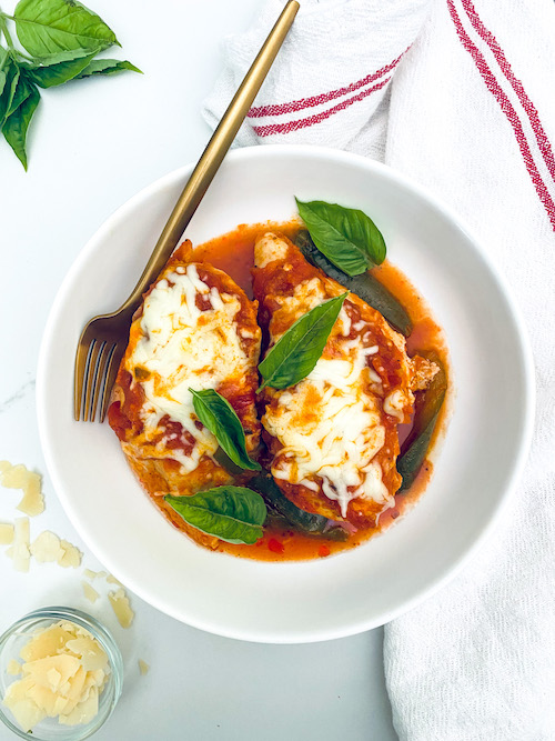 Marinara chicken breast topped with mozzarella in a white bowl.