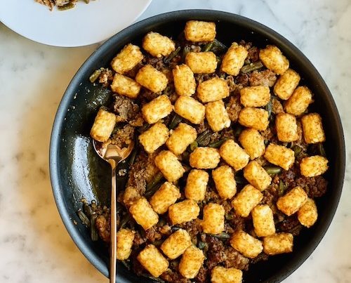 Sausage and green bean skillet topped with tater tots.
