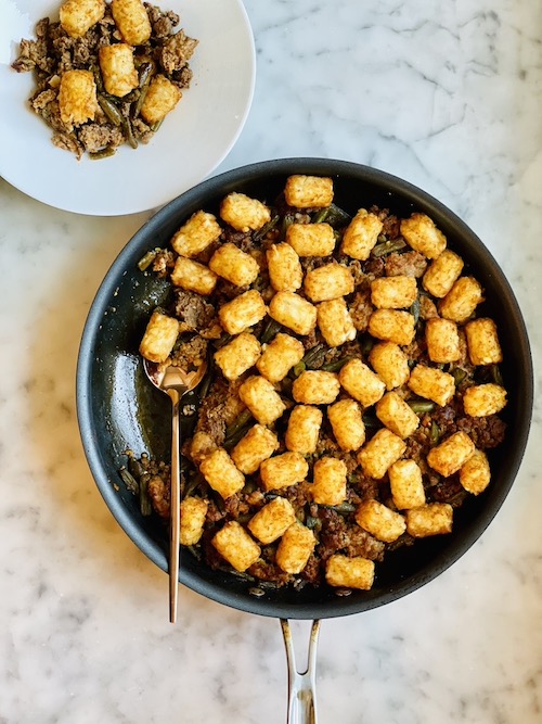 Sausage and green bean skillet topped with tater tots.