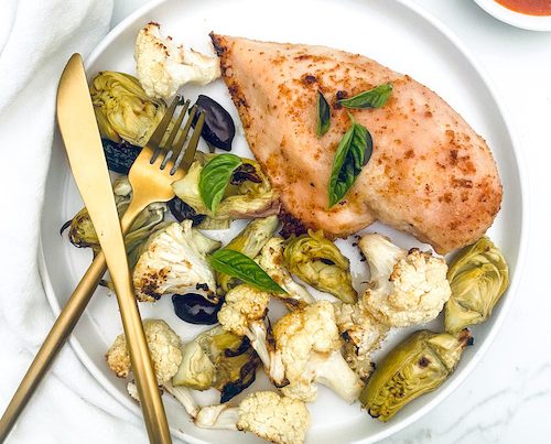 Italian chicken with roasted veggies on a white dinner plate.