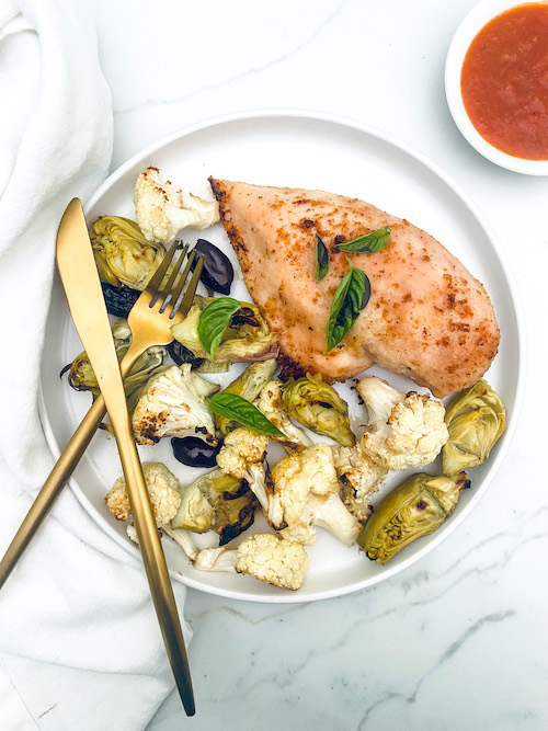 Italian chicken with roasted veggies on a white dinner plate.