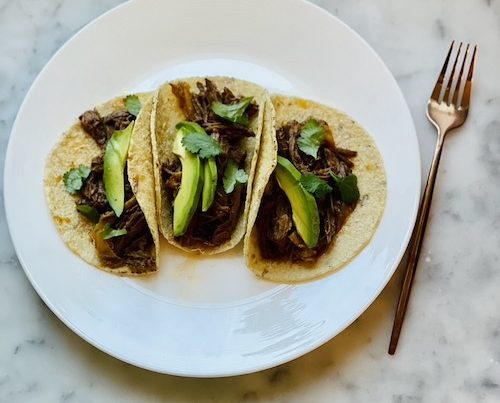 Chipotle beef and peppers in tacos with avocado and cilantro.