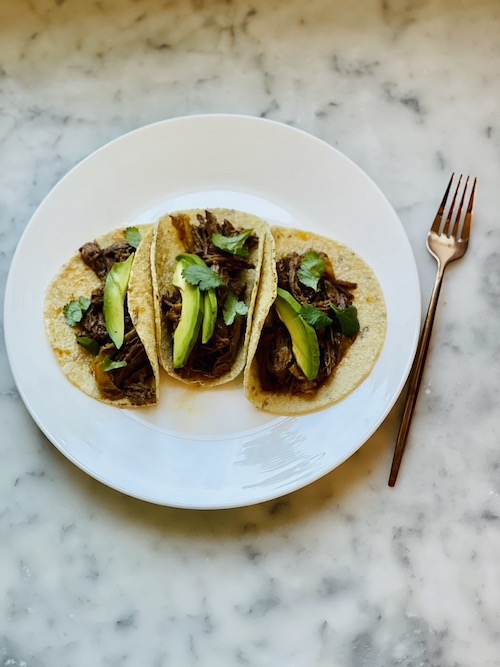 Chipotle beef and peppers in tacos with avocado and cilantro.