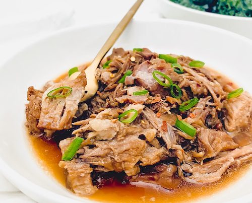 Shredded apple cider braised pork in a deep white bowl.