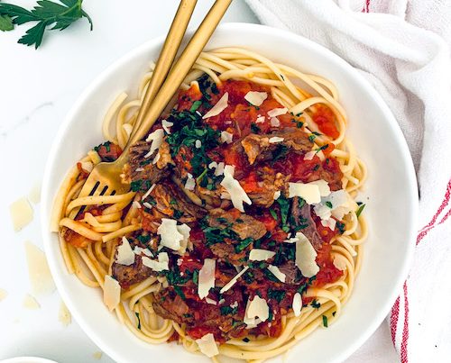 Beef rags and cheese over a large bowl of bucatini.