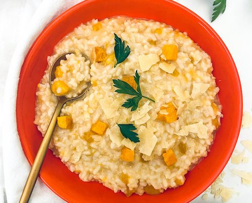 A deep red bowl filled with butternut squash risotto.