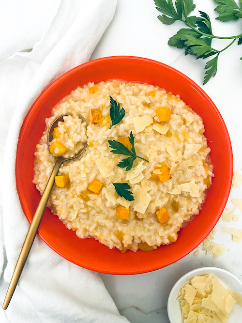 A deep red bowl filled with butternut squash risotto.