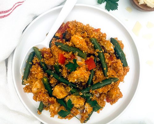 A white bowl filled with Italian chicken and green bean quinoa.