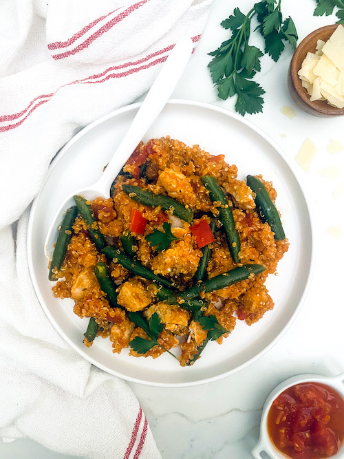 A white bowl filled with Italian chicken and green bean quinoa.