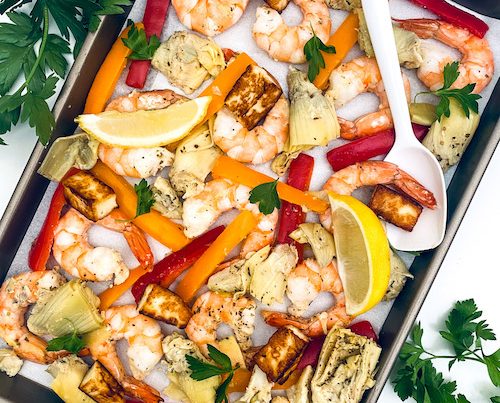 Shrimp and roasted peppers on a parchment lined baking sheet.