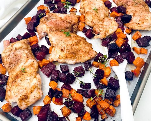 Chicken breast and roasted beets on a parchment lined baking sheet.