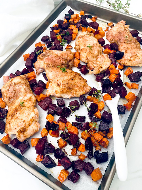 Chicken breast and roasted beets on a parchment lined baking sheet.
