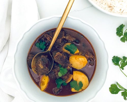 Carne guisada with potatoes in a white bowl.