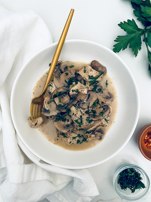Chicken and marsala mushrooms in a deep white bowl.