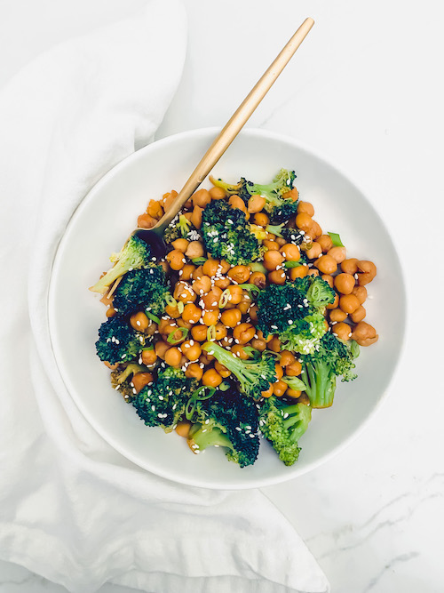 Honey Sriracha Chickpeas + Broccoli in a white bowl with a gold fork.