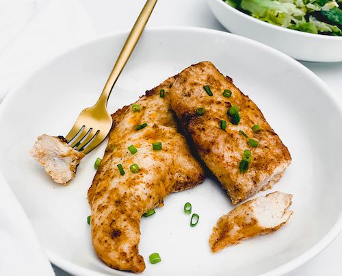 Two Dorito flavored chicken breasts in a white bowl.