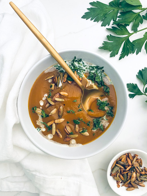 A white bowl filled with vegetarian autumn squash soup.
