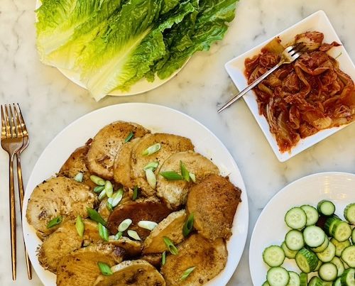 Ingredients for pork lettuce wraps on white plates.