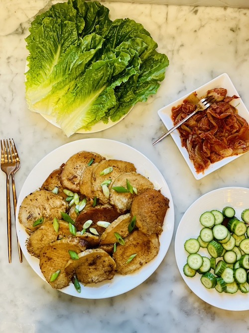Ingredients for pork lettuce wraps on white plates.