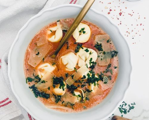 Tortellini soup with chives and cheese.