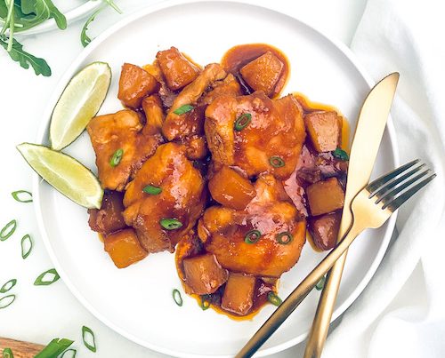 Spicy pineapple chicken thighs on a white dinner plate.