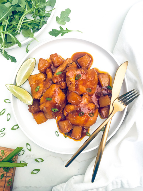 Spicy pineapple chicken thighs on a white dinner plate.