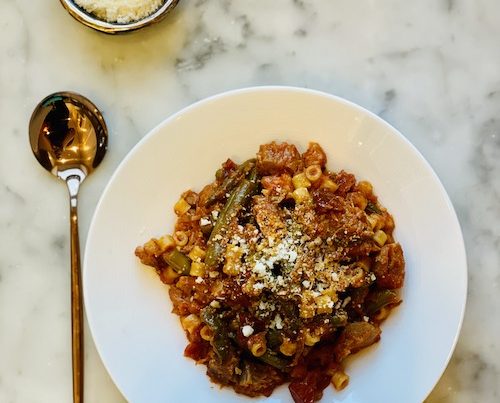 Pork and green bean stew in a large white bowl.