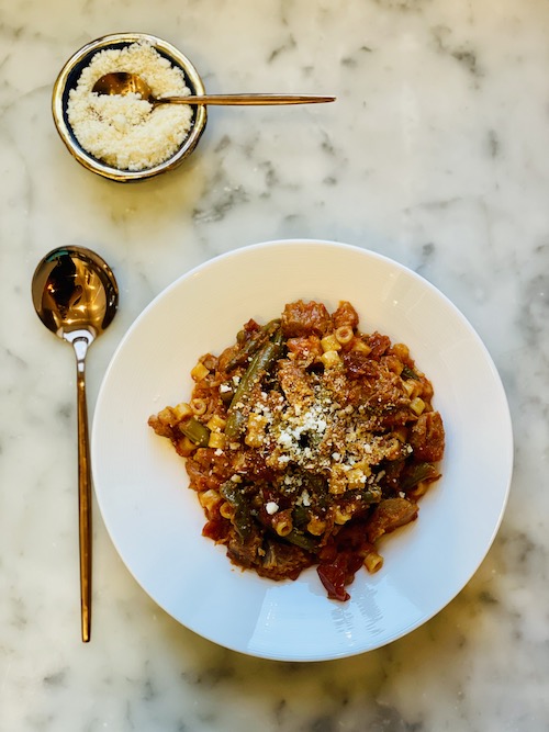 Pork and green bean stew in a large white bowl.