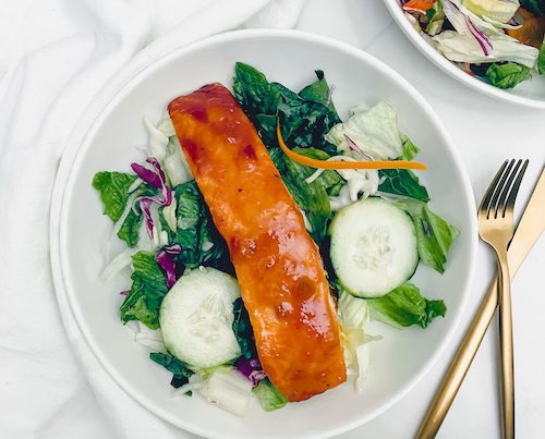 Peach glazed salmon over a fresh green salad.
