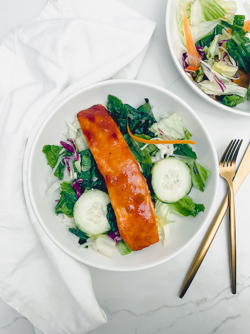 Peach glazed salmon over a fresh green salad.