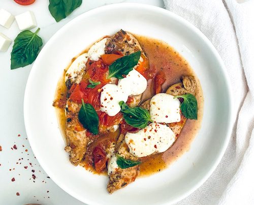 A white bowl filled with caprese chicken.