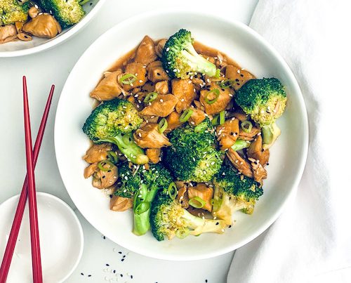 Chicken teriyaki with broccoli in a white bowl with chopsticks.