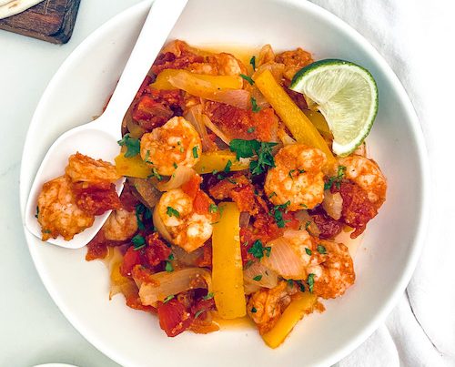 Shrimp and peppers for fajitas in a white serving bowl.