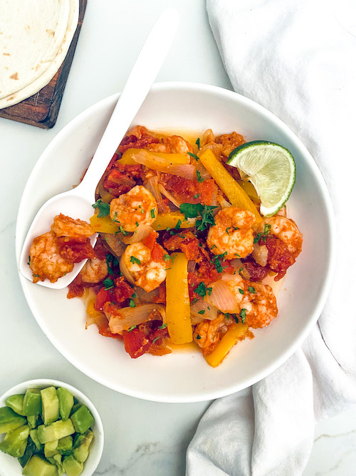 Shrimp and peppers for fajitas in a white serving bowl.