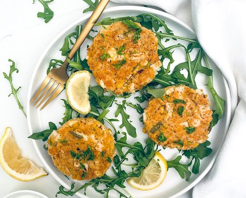 Vegetarian crab cakes on a white plate with arugula.