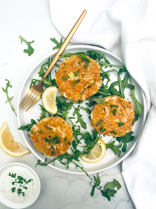 Vegetarian crab cakes on a white plate with arugula.