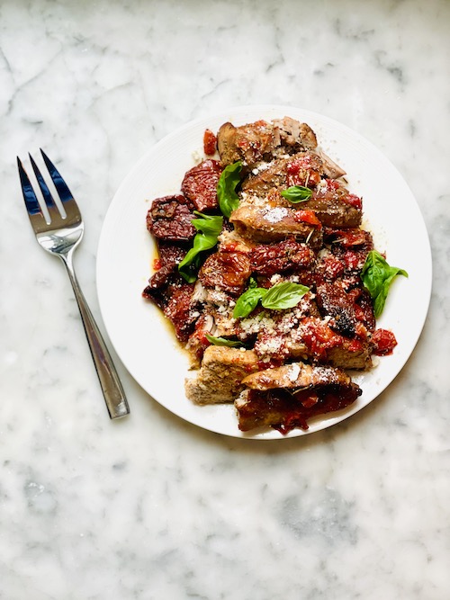 Sundried tomato pork chops on a plate with fresh basil.
