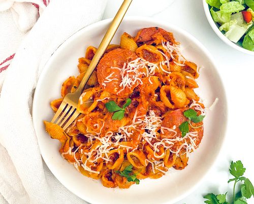 Pepperoni pizza pasta shells in a white bowl.