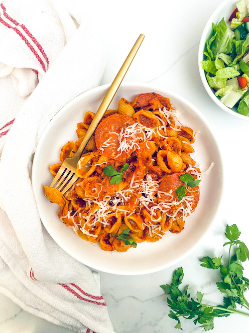 Pepperoni pizza pasta shells in a white bowl.