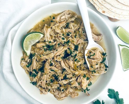 Shredded honey lime salsa verde chicken on a white platter.