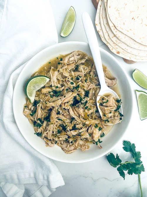 Shredded honey lime salsa verde chicken on a white platter.