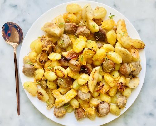 Crispy gnocchi with apples and brats on a white plate.